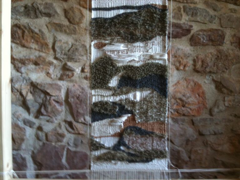 Tapisserie de Lexie primée, laines naturelles sur mur de pierre