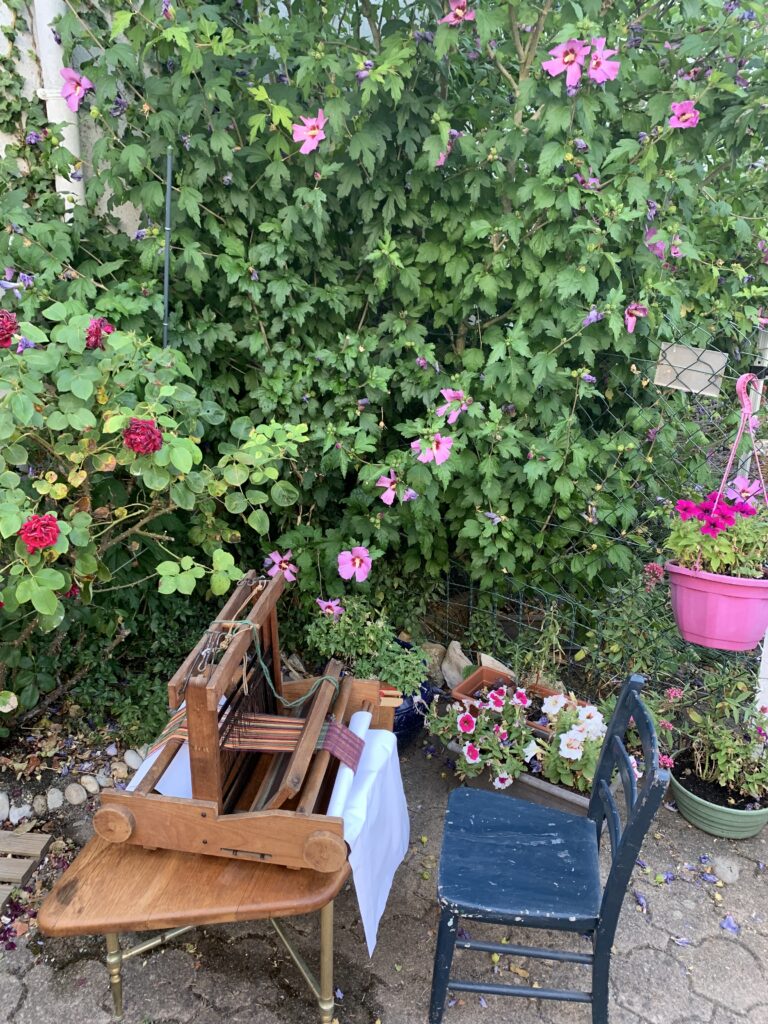 Petit métier à tisser pour enfant et sa chaise bleue, dans le jardin