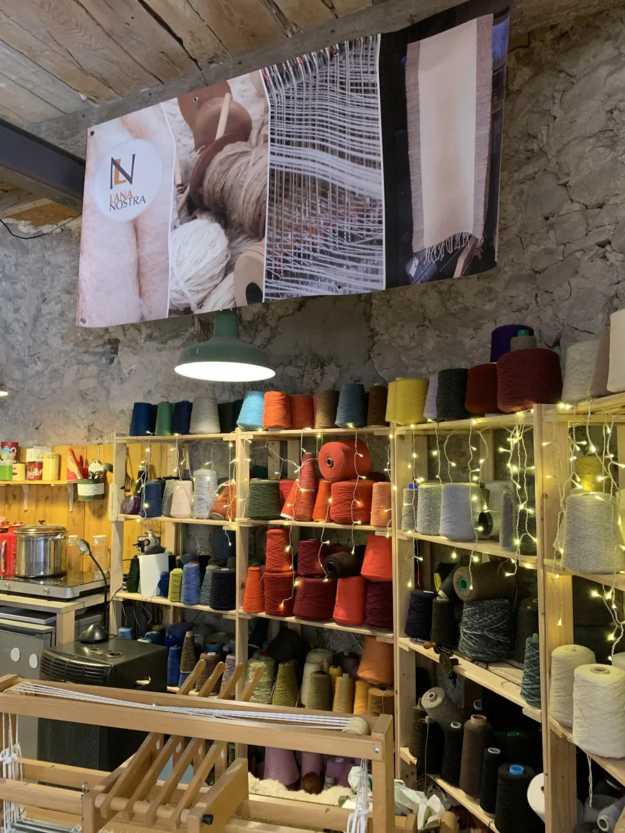 La boutique de l'atelier Lana Nostra : étagères de bobines de laine colorées et bannières tissées